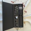 Coffret cadeau cuisine Sanakaza ouvert contenant le couteau Santoku 18 cm avec son étui et le tablier noir plié dans son alvéole.