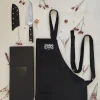 Coffret cadeau Sanakaza ouvert contenant le couteau Santoku 18 cm avec son étui et le tablier noir plié dans son alvéole.
