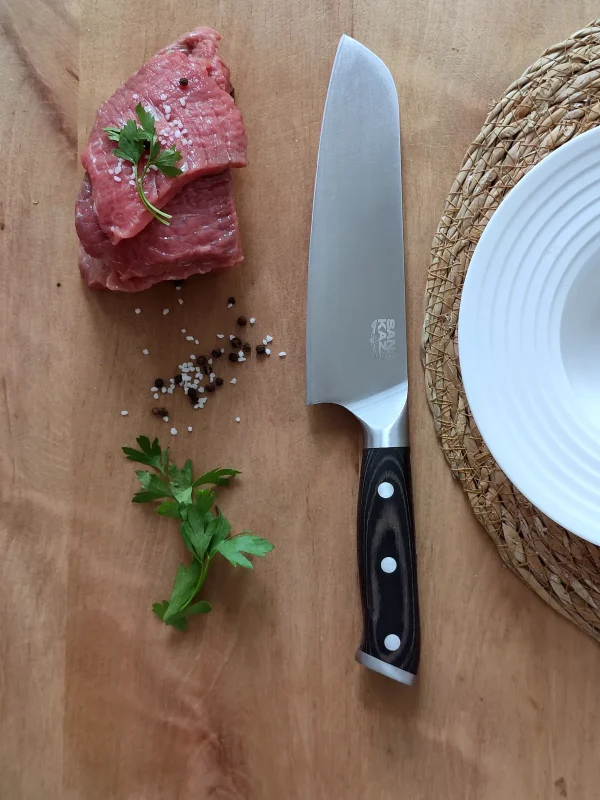 Couteau Santoku Sanakaza avec viande, persil et assiette blanche